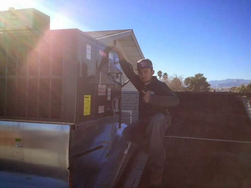 HVAC technician performing Air Duct Repair on a rooftop unit in Topsham